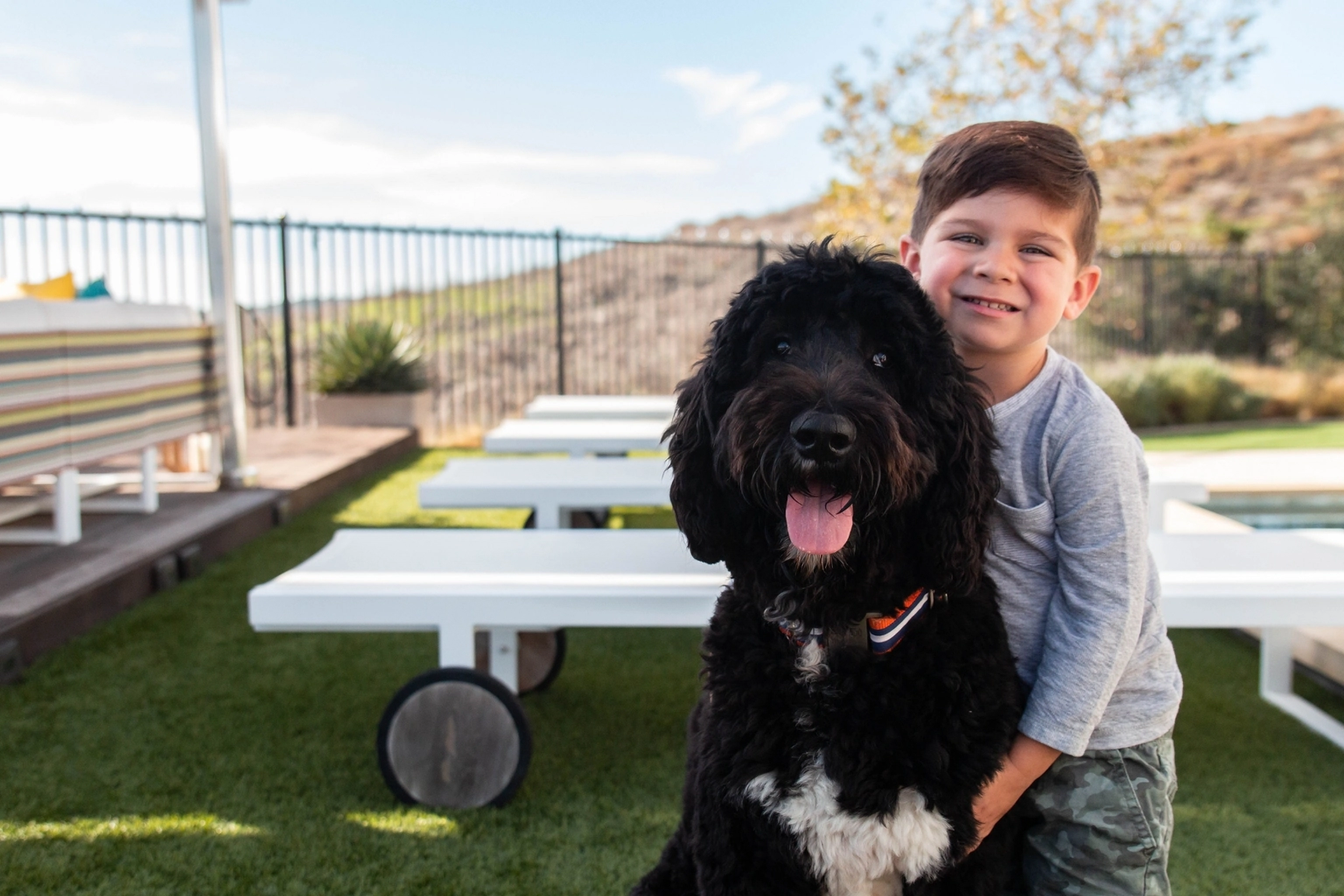 Happy child playing with dog on clean, safe artificial turf